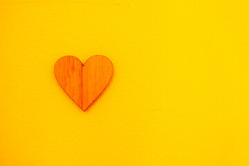 small wooden heart on a yellow background, horizontal