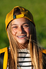 Portrait of beautiful young blonde girl in a yellow cap and a bracket on her teeth.
