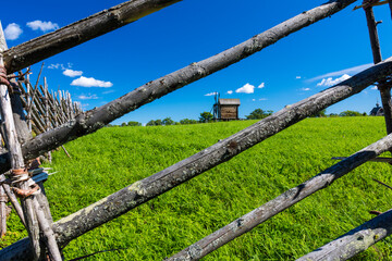 Fototapeta na wymiar Windmill with grass field behind wooden fence in Russia