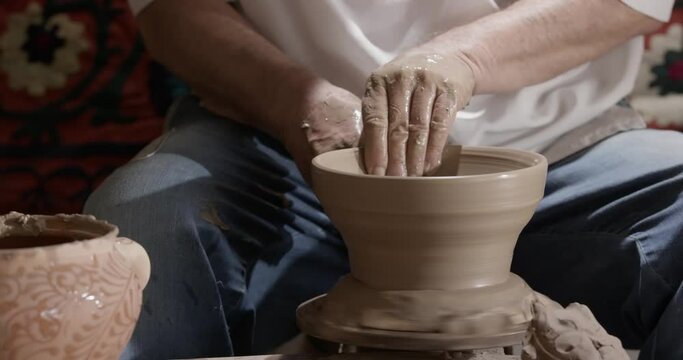 Hands of a master potter working on a potter's wheel in the manufacture of dishes