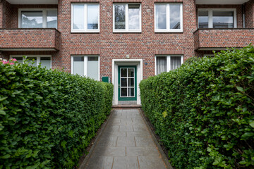 Front side of apartment house, entrance with hedges and pathway
