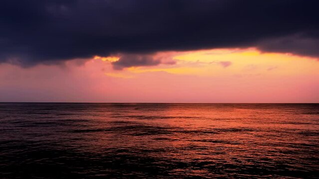 Sea waves with reflection of red sunset on the colors purple cloudy sky background. Beautiful sunlight with clouds, calm scene by the horizon evening, mid shot,  slow motion, panning, hd.ProRes 422 HQ