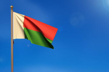 Madagascar. Flag blown by the wind with blue sky in the background.