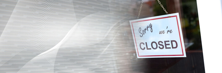 Closed sign hanging behind a store window; panoramic banner