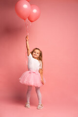 Obraz na płótnie Canvas little girl in a white t-shirt and a pink tutu with balloons on pink background