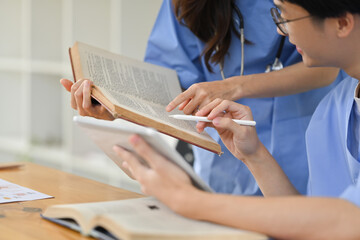 Two happy medical student reading books, preparing for university exams in library. Medical...