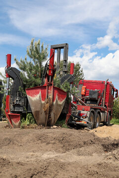 Tree transplanter heavy machine. machine for transplanting large trees. Planting large spruce trees in the park.  Landscaping, spring agricultural engineering, trees landing machines. Agrotechnology