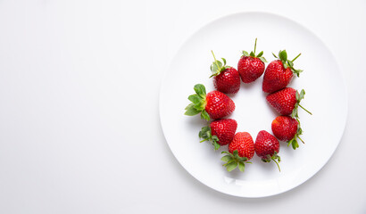 Fresh strawberries on a white plate, on a white background