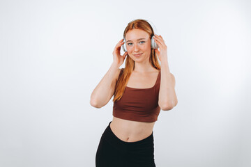 Obraz na płótnie Canvas young sporty red-haired girl isolated on white background, with headphones.