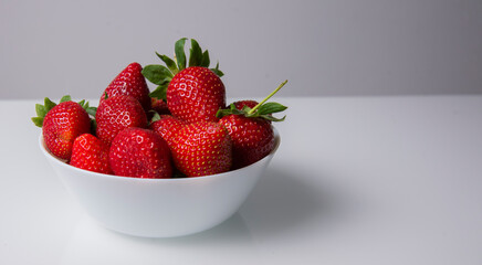 Fresh strawberries on a white plate, on a white background