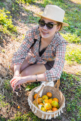 Cute thai girl smiling with orange basket in orange farm in Chiang Mai, Thailand