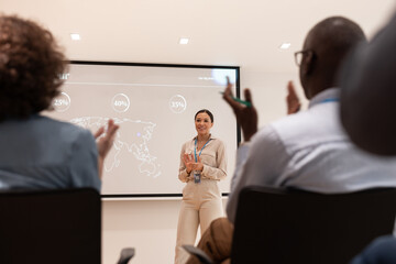 Business woman receiving applause at the end of a business conference presentation