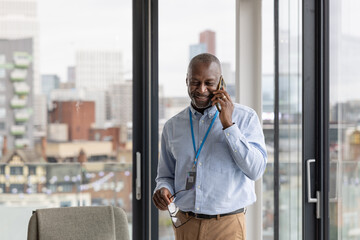 Senior black businessman in corporate office talking on smartphone 