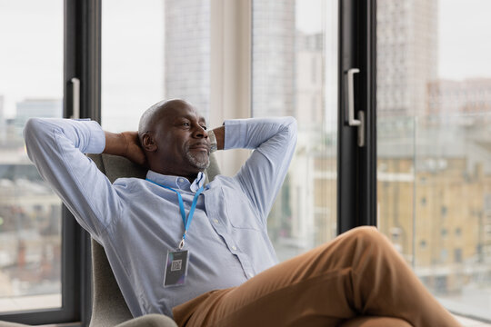 Senior black businessman in corporate office looking out at city skyline