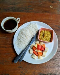Typical Sri Lankan breakfast dish called string hoppers with red lentil dahl and mix fruit salad with black coffee