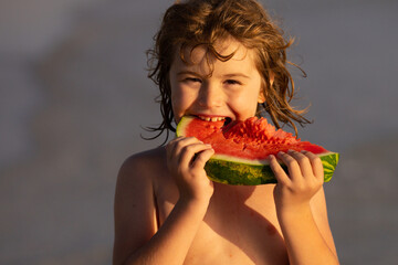 Vacation and traveling with kids. Summer watermelon fruit for children. Child play by the sea and eat watermelon. Little boy biting watermelon on beach. Kid is picking watermelon outdoor.