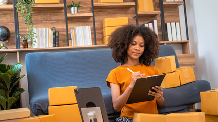 African American business woman working at warehouse preparing SME package box for delivery at small business home office.