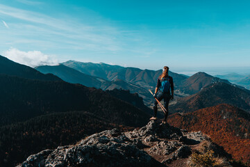 Girl on mountain peak with green grass looking at beautiful mountain valley in fog at sunset in summer. Landscape with sporty young woman, Travel and tourism.Mala Fatra mountains in Slovakia