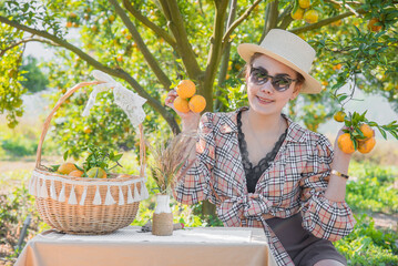Happy Cute thai girl holding oranges with orange basket in orange farm in Chiang Mai, Thailand.