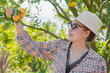 Happy Cute thai girl holding orange in orange farm in Chiang Mai, Thailand.