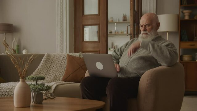 Thoughtful Elderly Man Using Laptop, grandpa browsing online
