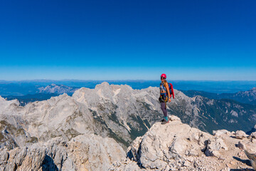 Woman standing at the top of the hill in mountains looking at wonderful scenery. Triglav, the highest slovenian mountain. Trgilav national Park. Slovenia. Europe.