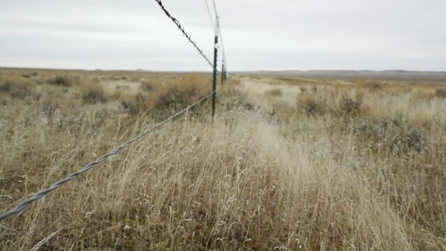 Jib up and down along long ranch fence on windy Montana day with grouse flag