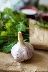Vertical photo of garlic on kraft paper, blurred background of other spices