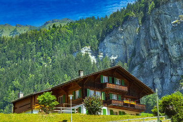 Old wooden house with flowers on the balcony in Swiss Alps