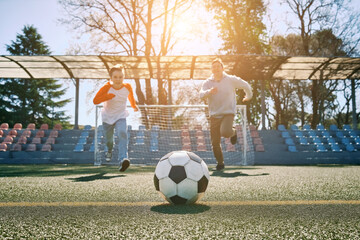 Father and Son play football on stadium, Happy family outdoors, bonding, family fun, players in...