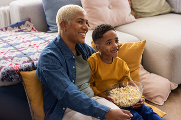 African American mother and son streaming a movie at home eating popcorn