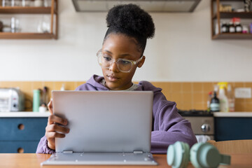 Teenager doing school work on a laptop in the kitchen