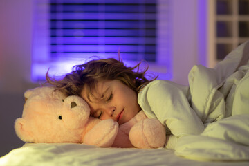 Good night sleep. Adorable kid sleeps in bed with a toy teddy bear. Sleeping child.