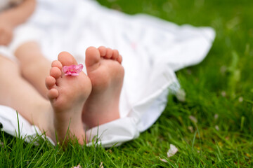 A child's feet on a picnic - a white blanket and green grass