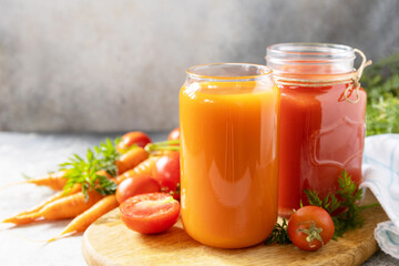 Vitamins drinks juice carrot and tomato. Tomato and carrot juice in a glasses on a stone table. Healthy lifestyle. Copy space.