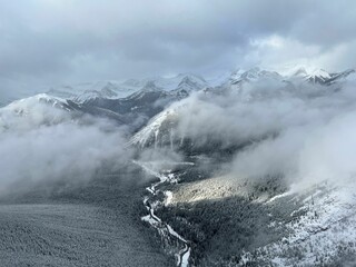 Bird's eye view of snowy mountains and valleys in a fog