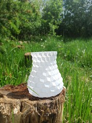 3D printed vase. 3D printed vase with green grass and bushes in the background