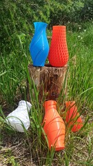 3D printed vase. 3D printed vase with green grass and bushes in the background