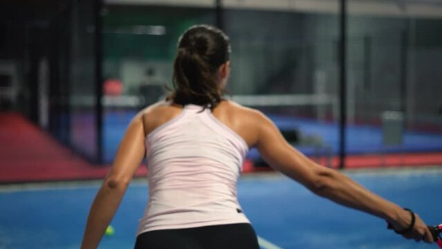 Young sportswoman and man couple playing padel tennis in slow motion. Hitting padel ball in slow mo at padel court.