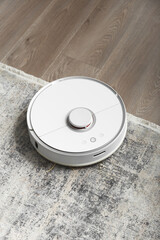 Modern robot vacuum cleaner on soft carpet in room