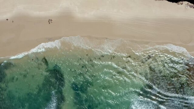 Aerial drone wide bird's eye top view shot of stunning crystal clear turquoise ocean water on the famous Sibauma beach with small waves and golden sand in Tibau do Sul, Rio Grande do Norte, Brazil