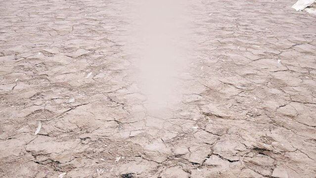 A camera following the swirling dance of a dust devil whirlwind across a dry and desolate landscape.