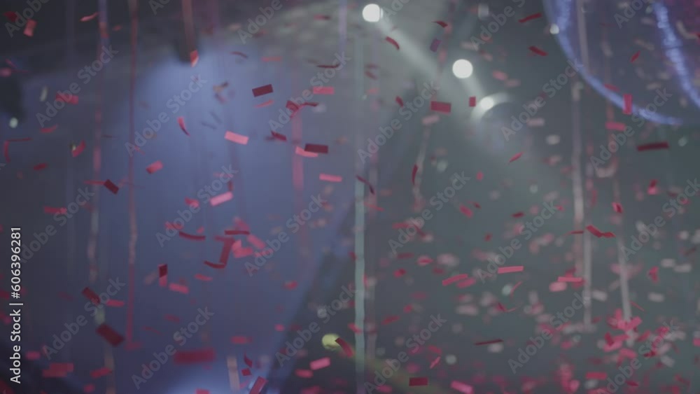 Poster slowmotion shot of red colored confetti falling down from the ceiling during a party with flashing l
