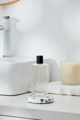 Bathroom concept with an unlabeled transparent bottle put on round-shaped podium and a candle...