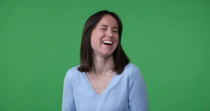 A woman of Caucasian ethnicity is seen laughing hysterically on a chroma key background. Her face is beaming with joy and she appears to be thoroughly enjoying herself.