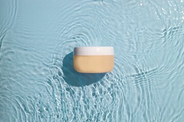 Close-up shot of a small white lotion container resting on a light pastel-colored background