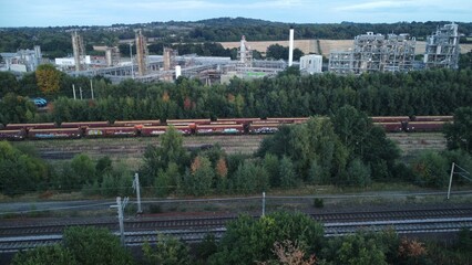 Aerial view of cargo railcars with graffiti, with industrial site in background