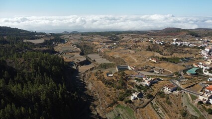 Fototapeta na wymiar Aerial drone view of farmland and a forest outside Vilaflor town under a blue cloudy sky