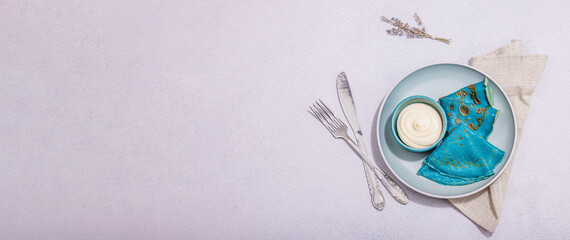 Thin blue pancakes with creamy sauce. Healthy vegan non lactose, gluten free food, breakfast concept