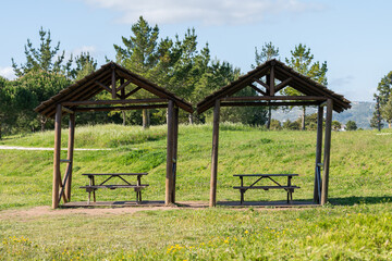 Scenic view of two wooden gazebos in the green field on the background of a forest